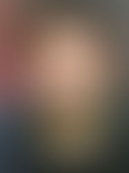 Man in black sweater stands before vertical wood panels; red light leaks on left, creating a contemplative mood.