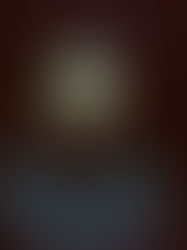 A man in a dark jacket stands in a dimly lit room with red and white lights in the background, creating a moody atmosphere.