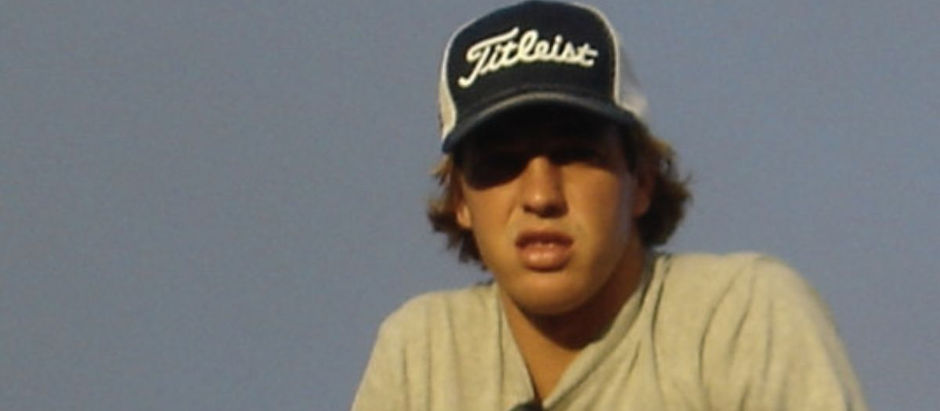 Young man in a Titleist cap and sunglasses against a blue sky, looking serious and slightly squinting.