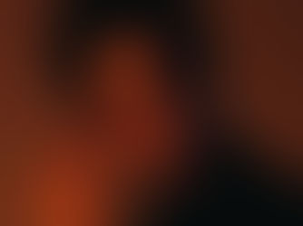 A man in a dark shirt poses against a brown backdrop. His gaze is pensive, with dramatic lighting highlighting his face and tousled hair.