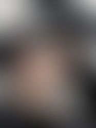 Man in a black cap and sunglasses, looking up. Background has geometric black and white patterns. Casual, contemplative mood.