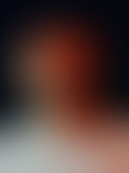 Man in a light shirt and cap stares ahead with a serious expression. Dark background with warm lighting highlighting his face.