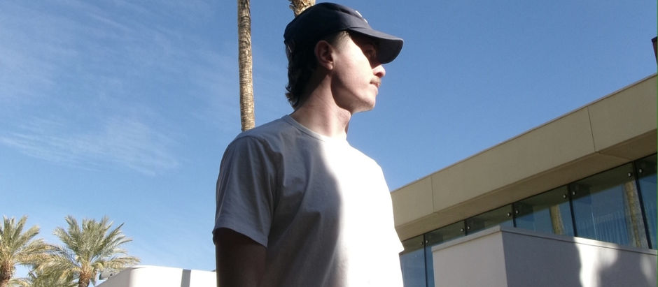Gabri returns with ‘If U Want’, a groove-led fusion of UK garage rhythms and atmospheric house production.nd cap stands outdoors, sunlight casting shadows. Palm trees and modern building in background under a clear blue sky.