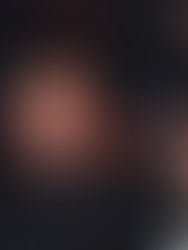 DJ with headphones around neck raises hands, smiling in a lively, dimly lit club with colorful lights and cheering crowd in background.