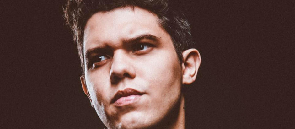 Close-up portrait of a young man with a serious expression against a dark background.