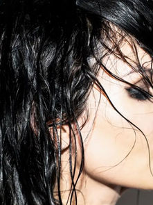 Wet-haired person in profile, bright light highlights black hair. Background is plain white. Makeup with dark eyeshadow and red lipstick.