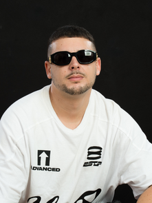 Man in sunglasses and white shirt with the text "Advanced" and "8 STP" sits against a black backdrop, exuding a cool, relaxed vibe.