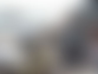 Crowd enjoying a sunny day at a seaside market with food stalls, beachgoers, and a pier in the background. Lively and bustling atmosphere.