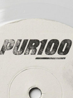Close-up of a white circular label or disc printed with PUR100 in bold black text on a plain light background.