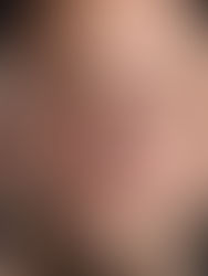 Close-up portrait of a bald man with a slight smile against a black background.