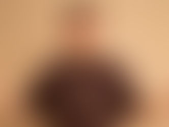 Young man in brown shirt with "TATSUDOSHI" text, arms open, neutral expression. Beige background enhances calm mood.