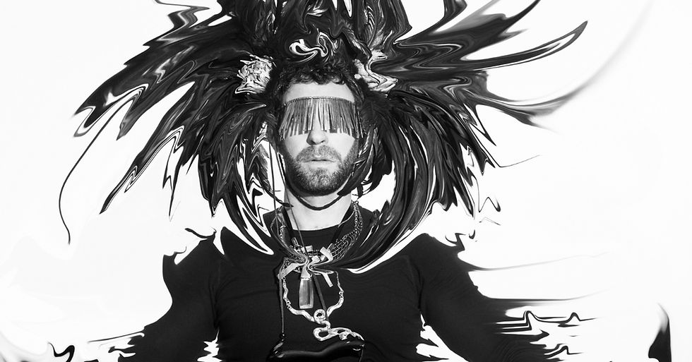 A person in black with a distorted and swirling headdress and sunglasses. The monochrome image has an artistic, surreal mood.
