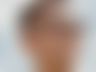 Man with black glasses looks pensively into the distance against a cloudy sky, reflecting a calm, thoughtful mood.