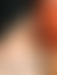 Person with a bat-wing tattoo faces away, in front of a glowing red neon sign. Dark setting, with their hand clenched in focus.