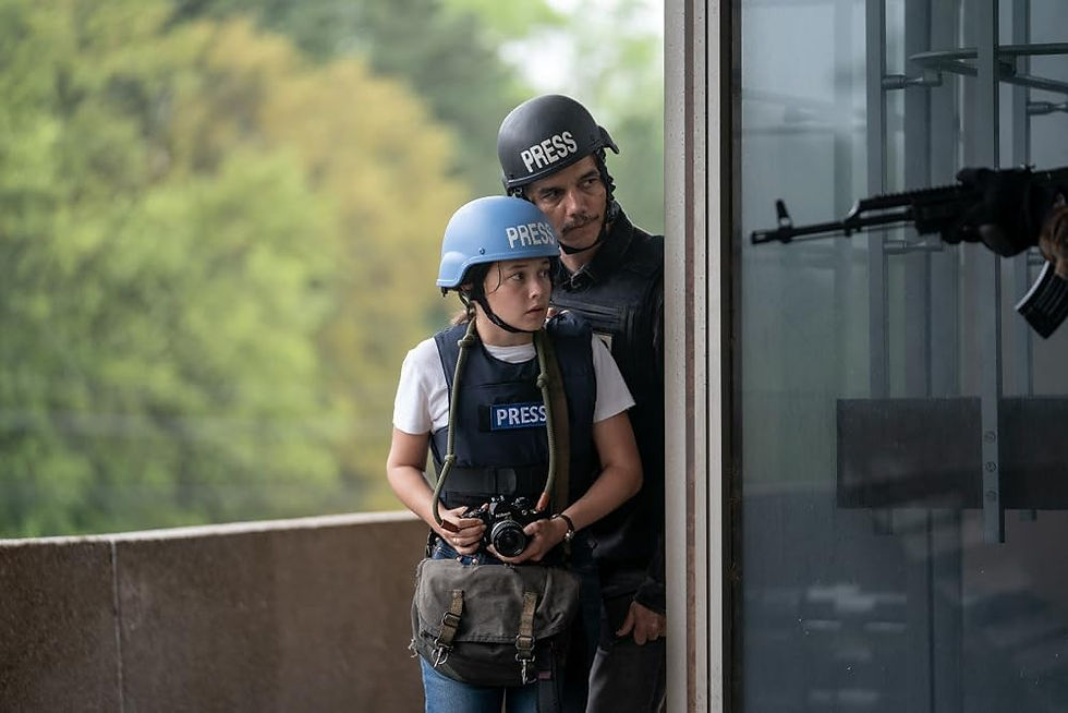 Two war reporters round a corner with a camera, protected by someone pointing a machine gun.