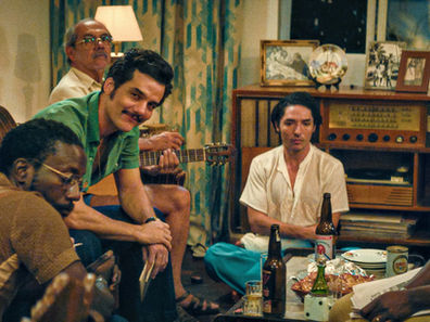 Wagner Moura and company sit around a coffee table strewn with drinks and snacks. 