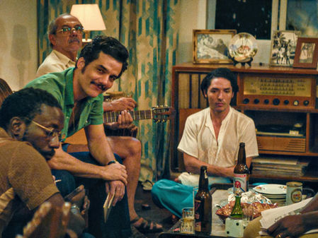 Wagner Moura and company sit around a coffee table strewn with drinks and snacks.