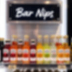 A sleek looking shelf displaying small bottles of alcohol branded "Bar Nips". The sign above the shelf also reads "Bar Nips"