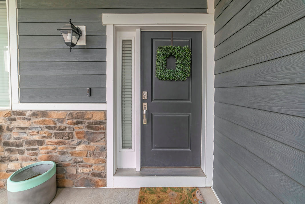 Entrance to a house with side light and gray front door decorated with wreath.jpg