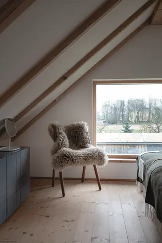EMOTIONALES DETAILFOTO IM FERIENHAUS SCHLAFZIMMER MIT STUHL UND SCHAFFELL