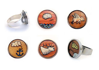 Images hand drawn on wood veneer set in silver rings.