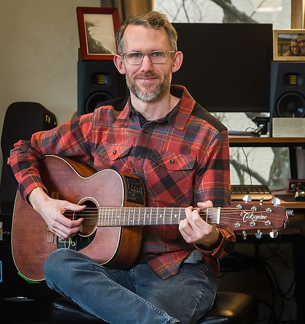 Bo Bestvina sitting and holding a guitar.