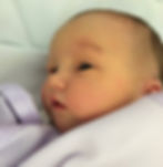 Newborn baby, born via c-section, with eyes open and wrapped in a purple blanket