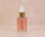 Frasco de 30ml com óleo rosé e válvula pump dourada em fundo pêssego.