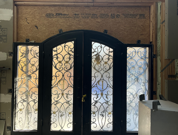 Traditional arched double entry door with decorative wrought iron glass panels before replacement with a modern front door.
 
