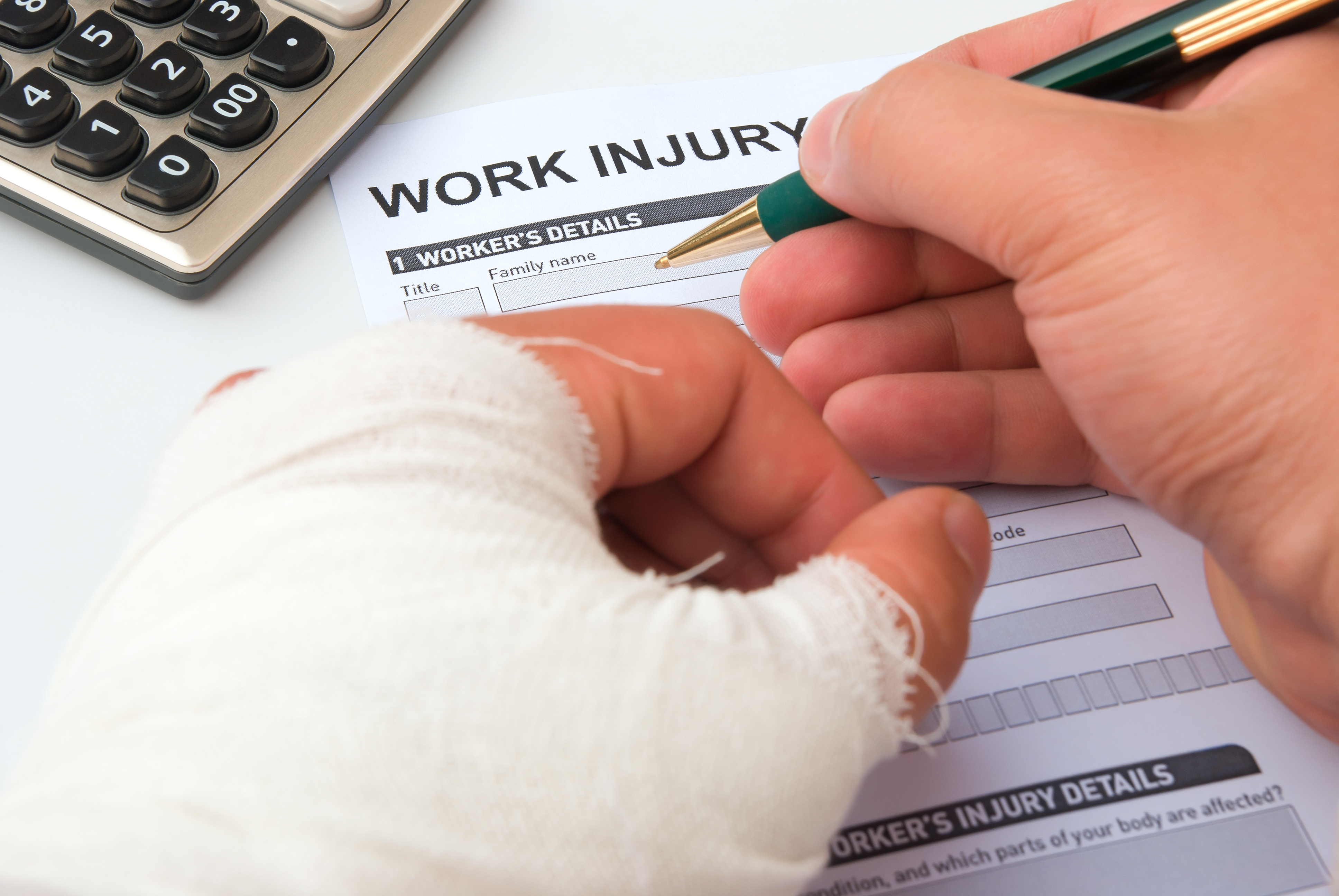 filling up a work injury claim form with a wrapped hand, calculator in corner, medical and