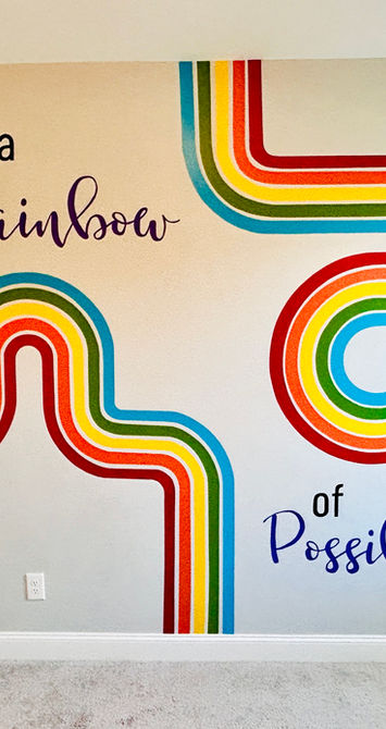 Hand-painted rainbow mural with colorful curved stripes and inspirational lettering in a child’s bedroom