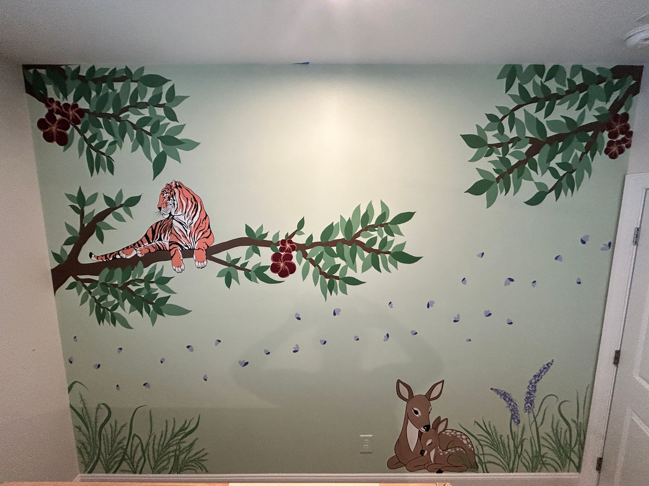 Hand-painted woodland mural with a tiger on a branch, leafy trees, flowers, and two fawns resting below.
