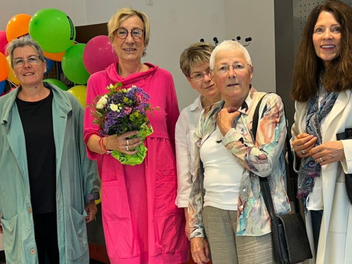 fünf Frauen schauen in die Kamera, eine hält einen Blumenstrauß