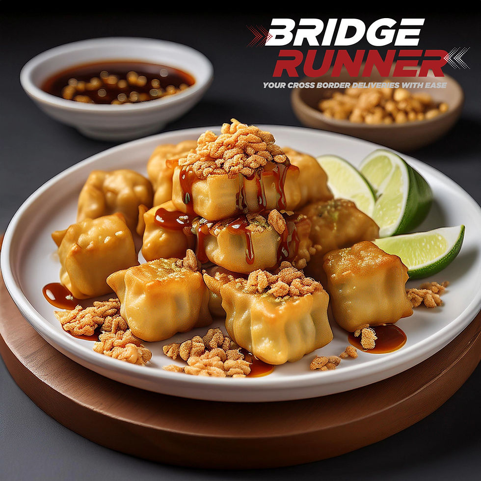 A beautifully arranged plate of Batagor, an Indonesian snack, featuring golden-brown fried tofu and wonton dumplings filled with fish paste, served on a white ceramic plate. The dish is drizzled generously with creamy peanut sauce and sweet soy sauce, garnished with freshly sliced lime wedges and crispy fried shallots. The background includes subtle wooden textures and a small bowl of peanut sauce