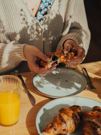 Kobiece dłonie trzymające rogalika przerywanego na pół