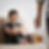 Sad boy sits curled up on a couch as a blurred adult holds a bottle of alcohol in the foreground.