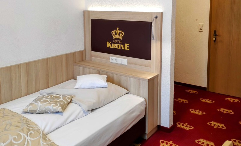 Cozy single room with crown logo on the headboard.
