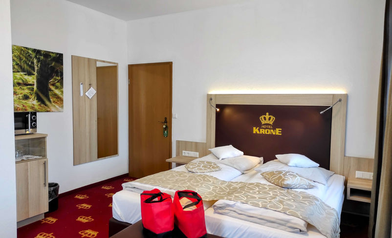 Modern double room with red carpet and crown logo.