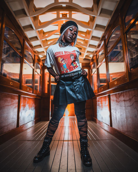 Young person poses in a hallway with a sunset; vintage t-shirt, skirt. LoveNikily Photos