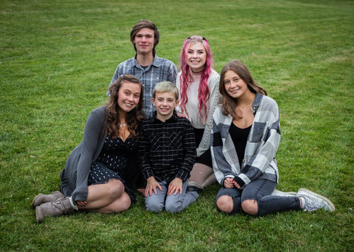 Group photo of a family smiling on green grass together. LoveNikily Photos.