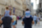 Two men walking side-by-side holding toddlers on their shoulders