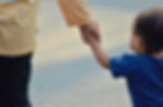 A babysitter holding a toddler's hand