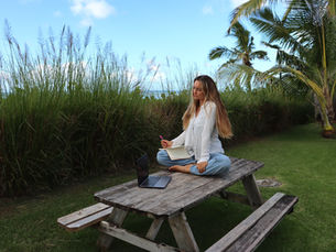 Kealia Media's founder, Kaya Waldman sitting on a picnic table in the yard writing in a journal.