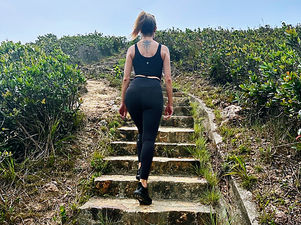Woman walking up stone steps surrounded by greenery, symbolizing a journey of healing and personal growth.