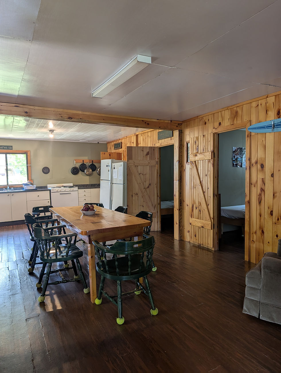 lakehouse-kitchen pine walls, large harvest table and green captains chairs
