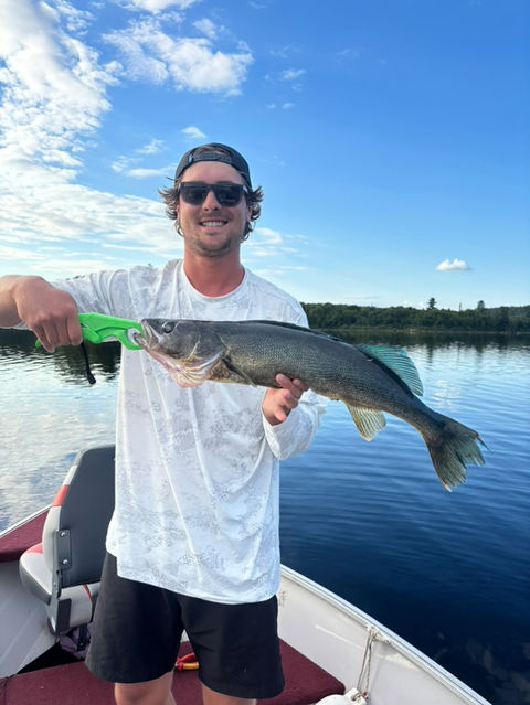 Man standing in a boat holding a walleye