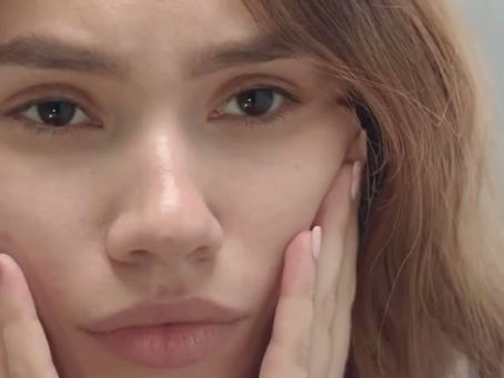 A woman assessing the condition of her skin with a concerned look on her face.