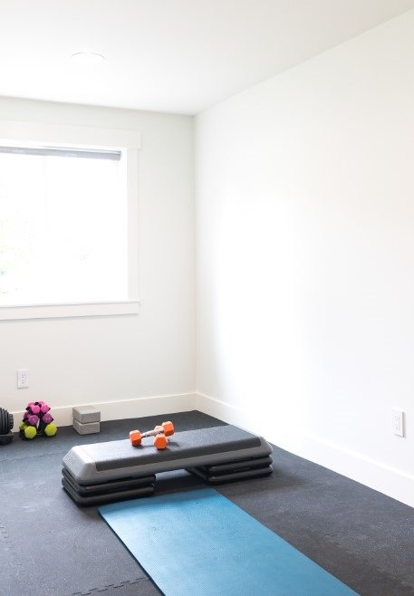 A home gym with rubber flooring and window.