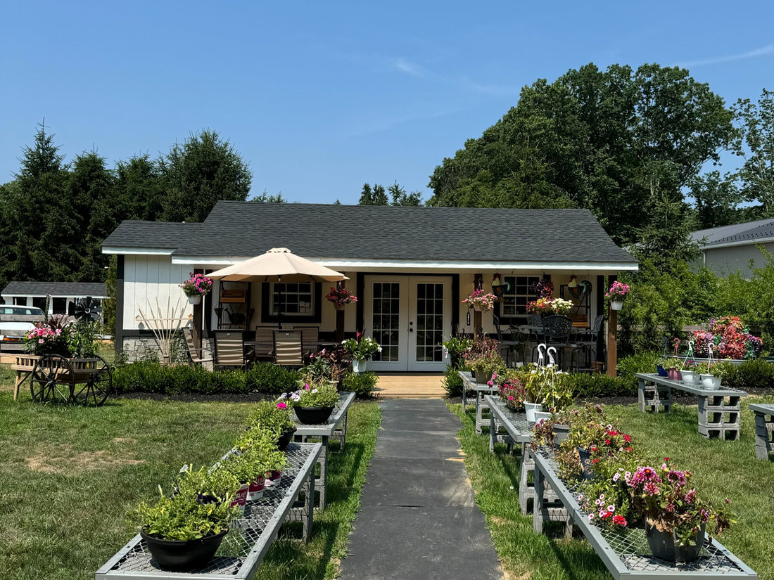 The JR's Cattle Ranch farm stand in summer, with flower beds lining the front walkway