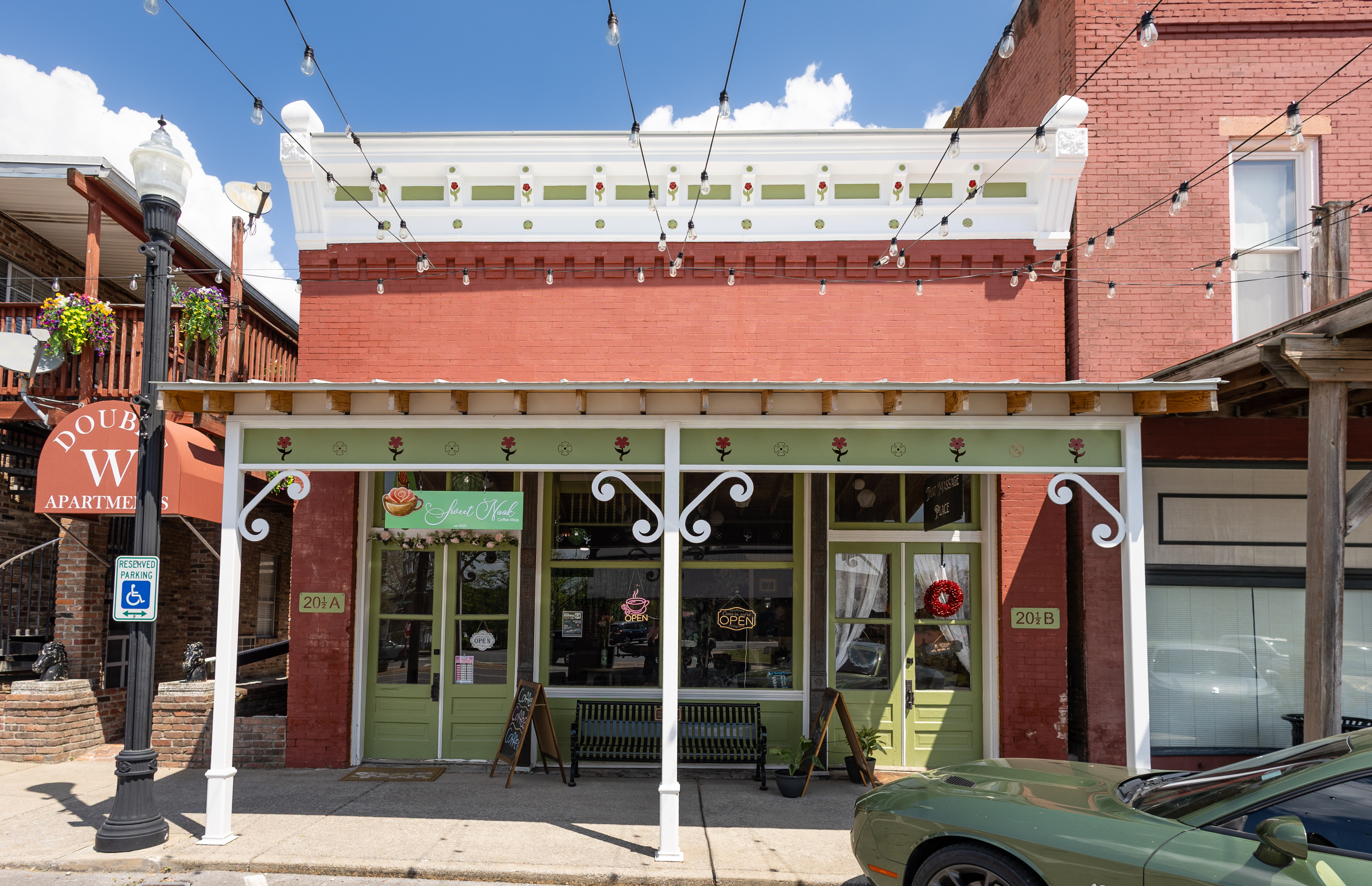 The colorful storefront of Sweet Nook Coffee Shop sits along Wartrace's historic downtown with decorative trim and string lights overhead.